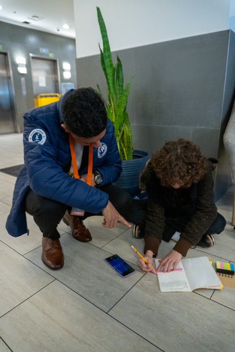 Mau kneeling beside a student to review her notebook